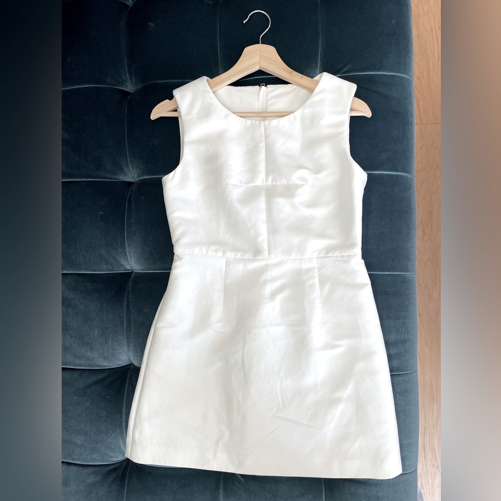 A unique white cocktail dress with an architectural designand floral embroidery.